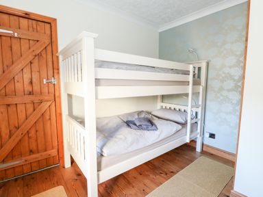 A bedroom with a white bunk bed and wooden door at 57 Southend Road in Hunstanton