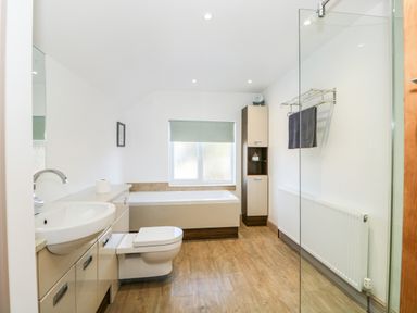 A bathroom with a sink a toilet a bathtub a window a towel rack and a cabinet at 57 Southend Road in Hunstanton