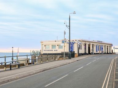 A street view of the Waterside Bar building near the sea with railings and a lamp post at 57 Southend Road in Hunstanton