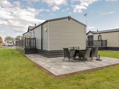 An outdoor patio area with a table and six chairs next to a mobile home at Happy Daze Carnaby near Bridlington