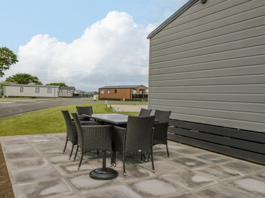 An outdoor patio with a table and six chairs beside a mobile home at Happy Daze Carnaby near Bridlington
