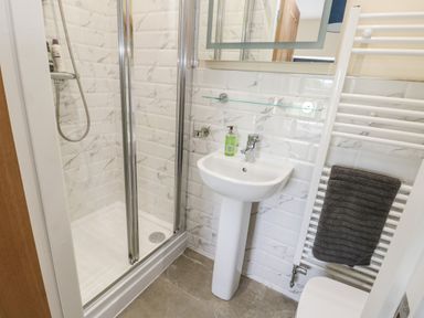 A bathroom with a shower enclosure sink with soap dispenser and heated towel rail at 8 Llwyn Onn in Llanfairpwllgwyngyll