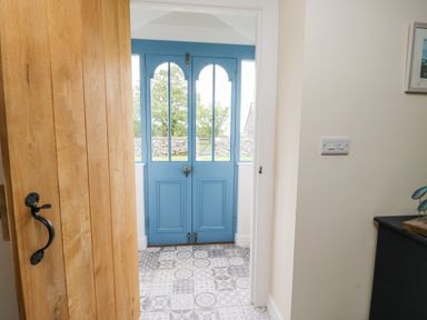 An entrance area with a partly open wooden door blue front doors and patterned floor tiles at 8 Llwyn Onn in Llanfairpwllgwyngyll