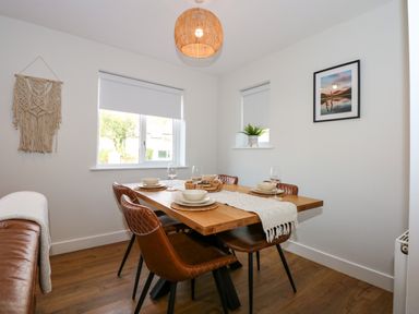 A dining area with a wooden table and four brown chairs with place settings at Aran in Beddgelert