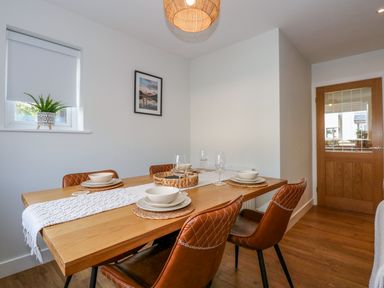 A dining room with a wooden table set for four and brown chairs at Aran in Beddgelert