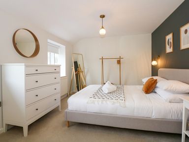 A bedroom with a bed chest of drawers wall mirror standing mirror and clothing rack at Aran in Beddgelert