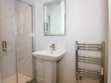 A bathroom with a shower enclosure sink with faucet mirror and heated towel rail at Aran in Beddgelert
