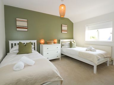 A bedroom with two single beds a chest of drawers and a window at Aran in Beddgelert