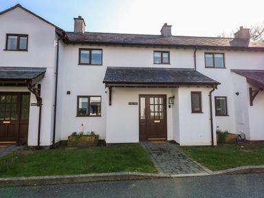 A front view of a white two story house with brown windows doors and a small porch at Craig y Llan in Beddgelert