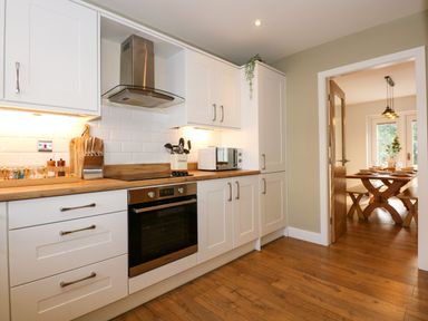 A kitchen with white cabinets wooden countertops an oven a microwave and cooking utensils at Craig y Llan in Beddgelert