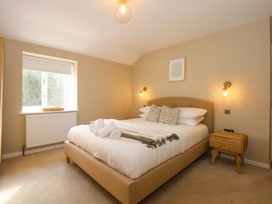 A bedroom with a bed two pillows two wall lamps a window and a wooden bedside table at Craig y Llan in Beddgelert