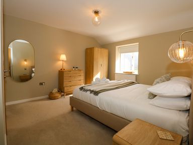 A bedroom with a bed chest of drawers wardrobe and mirror at Craig y Llan in Beddgelert