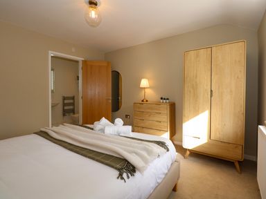A bedroom with a bed a wooden wardrobe and chest of drawers with a lamp at Craig y Llan in Beddgelert