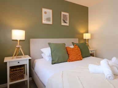 A bedroom with a bed with three pillows and two bedside tables with lamps at Craig y Llan in Beddgelert