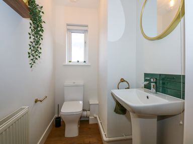 A small bathroom with a toilet, sink, mirror, and a small window at Craig y Llan in Beddgelert
