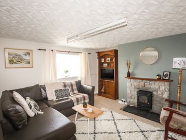 A living room with a leather corner sofa wooden cabinet and a stone fireplace at Cwm Ceiliog Annex Llanaelhaearn near Trefor