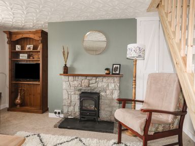 A living room with a stone fireplace a wooden bookshelf a lamp a chair and a staircase at Cwm Ceiliog Annex in Llanaelhaearn near Trefor