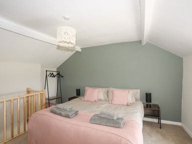 A bedroom with a double bed with pink pillows and grey towels on a pink blanket at Cwm Ceiliog Annex Llanaelhaearn near Trefor