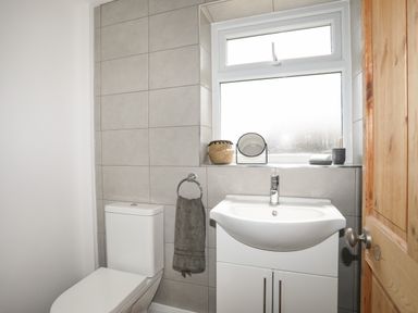 A bathroom with a toilet sink cabinet and a window at Cwm Ceiliog Annex Llanaelhaearn near Trefor