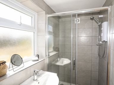 A bathroom with a sink a window and a glass enclosed shower at Cwm Ceiliog Annex in Llanaelhaearn near Trefor