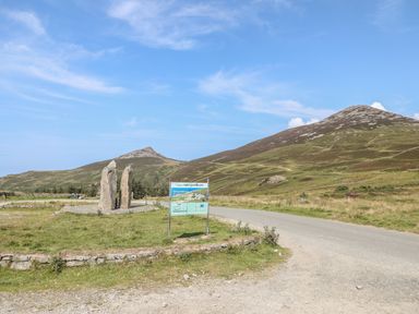 Two tall standing stones near a road with grass and hills in the background at Cwm Ceiliog Annex in Llanaelhaearn near Trefor