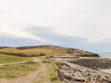 A coastal path next to rocky shoreline and grassy hills at Cwm Ceiliog Annex in Llanaelhaearn near Trefor