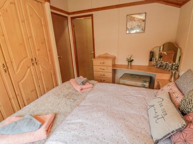 A bedroom with a bed pillows towels wooden wardrobes drawers and a vanity mirror at 4 The Oaks in Swarland