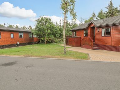 Two wooden cabins with steps and small trees on a grassy plot at 4 The Oaks in Swarland