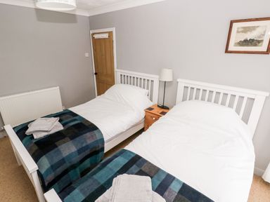 A bedroom with two single beds with white frames and plaid blankets at Ty Cwtch in Tenby