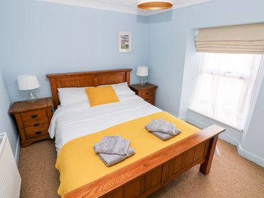 A bedroom with a wooden bed and two bedside tables with lamps at Ty Cwtch in Tenby