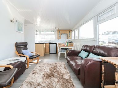 A sitting area with leather chairs and sofa next to a dining table and kitchen at Wagtails Norton near Dartmouth