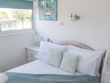 A bedroom with a bed pillows nightstand and window at Wagtails in Norton near Dartmouth