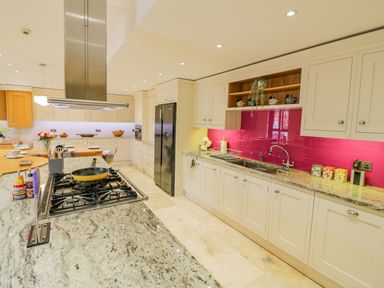 A kitchen with granite countertops gas stove and bright pink backsplash at The Stables in Belbroughton