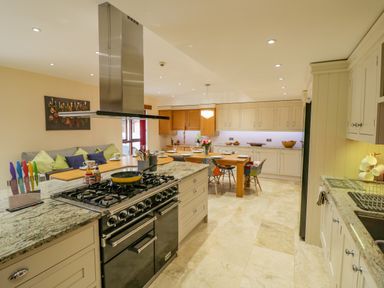 A kitchen with a stovetop island and a dining table with chairs at The Stables in Belbroughton