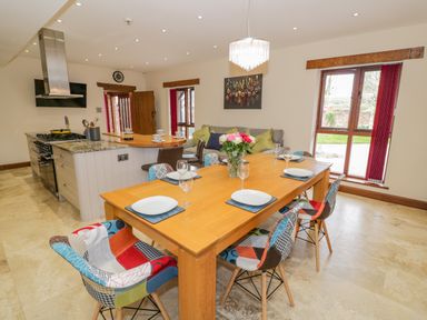 A kitchen and dining area with a wooden table set for six and patchwork chairs at The Stables in Belbroughton