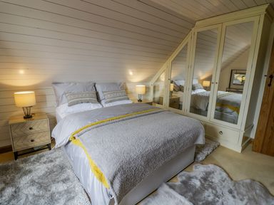 A bedroom with a double bed flanked by two lamps on bedside tables and a mirrored wardrobe at The Stables in Belbroughton