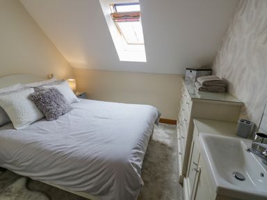 A bedroom with a bed pillows and bedside lamp under a skylight window at The Stables in Belbroughton