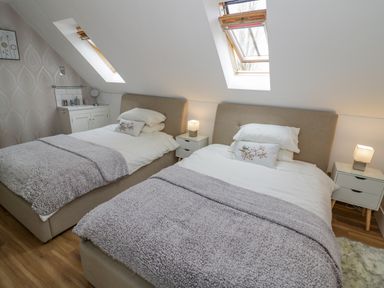 A bedroom with two single beds under skylights with bedside tables and lamps at The Stables in Belbroughton