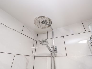 A shower area with dual shower heads and white tiled walls at The Annex in Ulverston