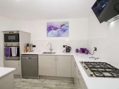 A kitchen with stainless steel appliances a gas stove a wall oven and purple kitchen accessories at The Annex in Ulverston