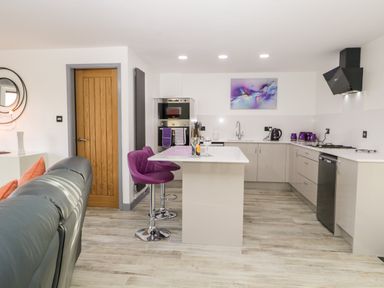A kitchen with a central island with purple stools and a wooden door at The Annex in Ulverston