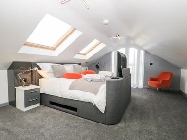 A bedroom with a bed with orange pillows and skylight windows at The Annex in Ulverston