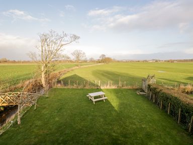 A backyard with a picnic table a small wooden bridge and a field beyond at The Annex in Ulverston