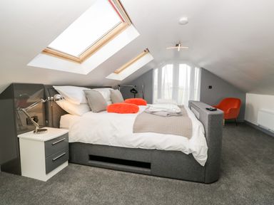 A bedroom with a bed under skylights and a bedside table with a lamp at The Annex in Ulverston