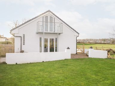 A white house with glass doors and a small balcony overlooking a green lawn at The Annex in Ulverston