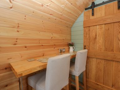 A wooden table with two high chairs and a sliding wooden door in a small room at Dew Pond in Blagdon