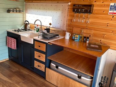 A kitchen with a sink stove kettle dish rack and hanging wine glasses at Dew Pond in Blagdon
