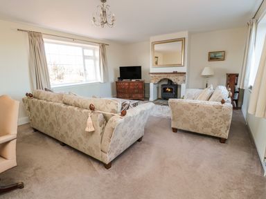 A living room with two patterned sofas a fireplace and a television at Thistleyhaugh Cottage in Longhorsley near Longframlington