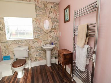 A bathroom with a toilet and sink and a towel rack with towels at Thistleyhaugh Cottage in Longhorsley near Longframlington