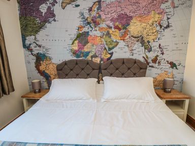 A bedroom with a bed and two pillows with a world map on the wall at Thistleyhaugh Cottage in Longhorsley near Longframlington